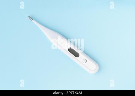 Electronic body thermometer on blue background. Modern termometer with digital display, diagnostic instrument Stock Photo