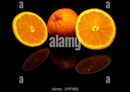 Two  half and an orange isolated on black with reflections Stock Photo