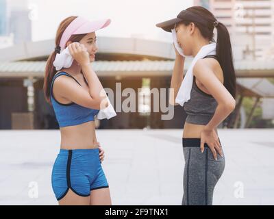 Two healthy woman runners in sportswear talking in city background after running exercise in the morning. Concept of women fitness and lifestyle. Stock Photo