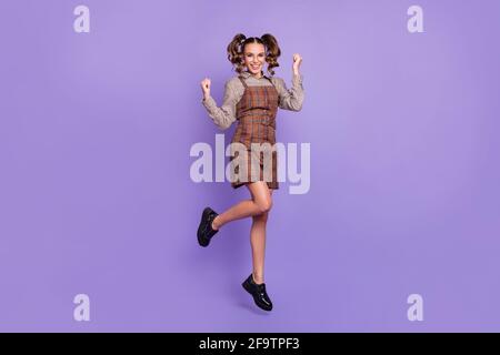 Full size photo of astonished girl jumping fists up celebrate have good mood isolated on violet color background Stock Photo