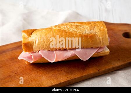 Homemade Parisian Jambon-Beurre Sandwich on a rustic wooden board, side view. Close-up. Stock Photo