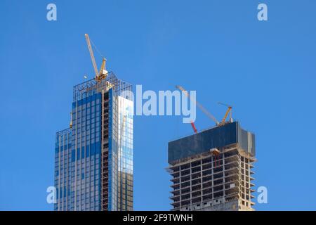 Moscow. Russia. April 18, 2021. Tower cranes atop an unfinished skyscraper against a clear blue sky during the day. The concept of the construction Stock Photo