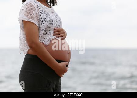 Pregnant woman in a blue dress on sea and sky blurred background and have copy space. Stock Photo