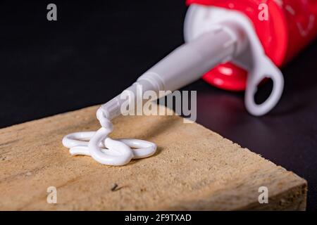 Silicone leaking from the plastic tube. A material for sealing in a domestic bathroom. Dark background. Stock Photo