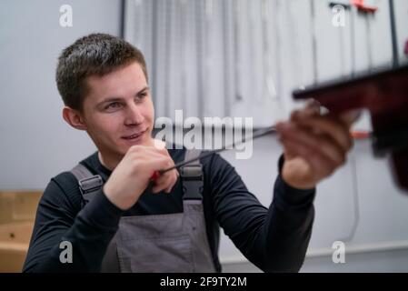 Portrait of concentrated young dent removing specialist on car repair station Stock Photo