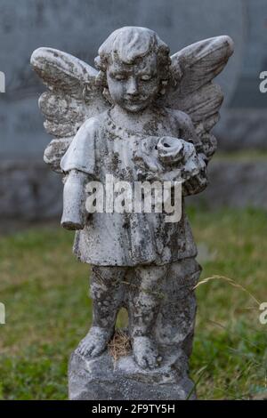 Stone Angel Watching Over a Quiet Cemetery in Quebec, Canada. Years of being out in the elements are shown in the wear on the statute and the missing Stock Photo