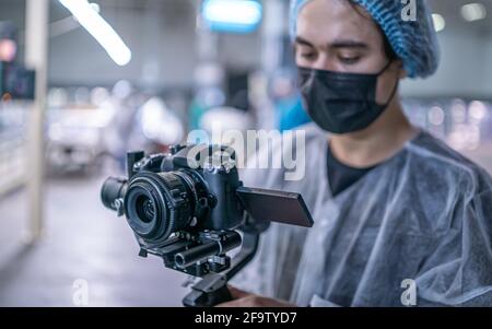 Young operator in medical protective suit with camera Stock Photo