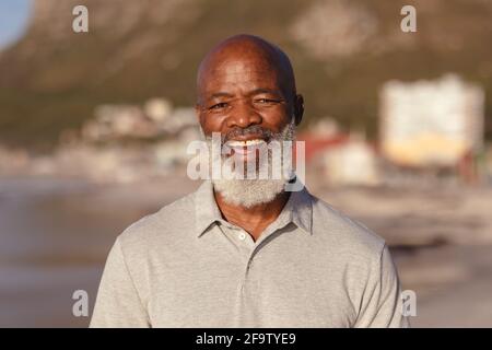 Portrait of senior african american man smiling while standing on the beach Stock Photo