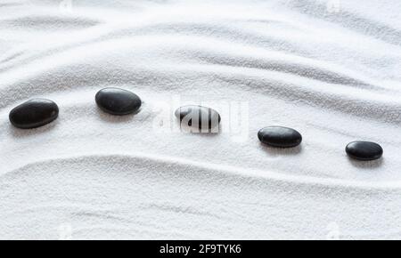 Zen pebbles on white sand pattern Stock Photo