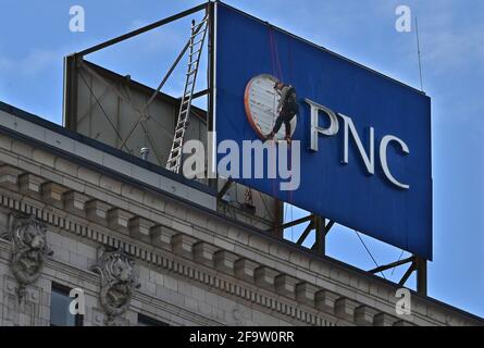 A man hangs from the top of the PNC sign on the PNC Bank building to change the light bulbs. Stock Photo