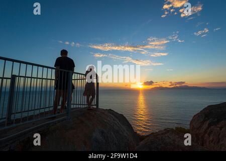 Two people watching the sunrise from the Horseshoe Bay Rotary Lookout, Bowen, Queensland, QLD, Australia Stock Photo