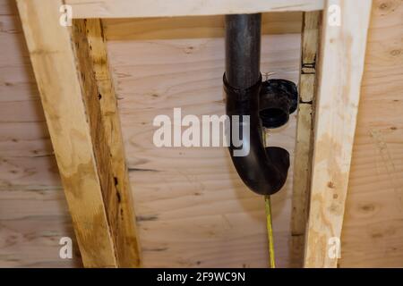 PVC plastic toilet sewer drain pipe in the plumber gluing, on wooden frame beam of house Stock Photo