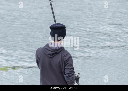 young man prepares fishing rod on dock Stock Photo