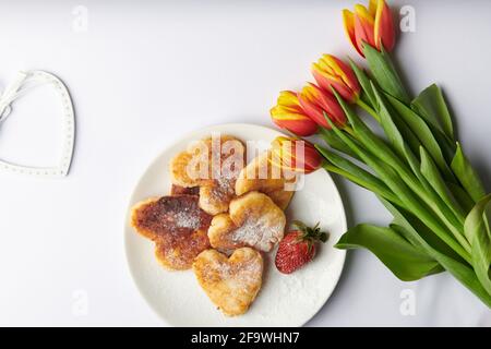 a bouquet of tulips with strawberries cheesecakes in the form of hearts  Stock Photo