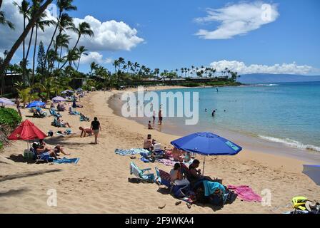 tourists relax under umbrellas and swim and play on the sandy sunny kaanapali beach west of the town of Lahaina on the island of Maui Hawaii usa Stock Photo