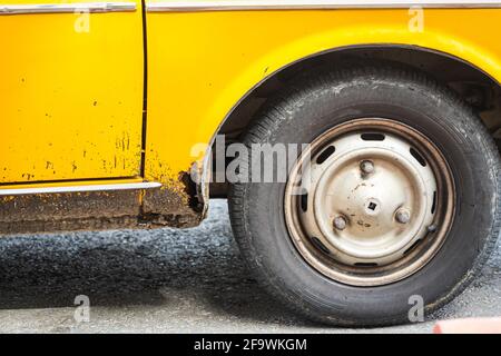 Car wheel on an old yellow rusted car Stock Photo