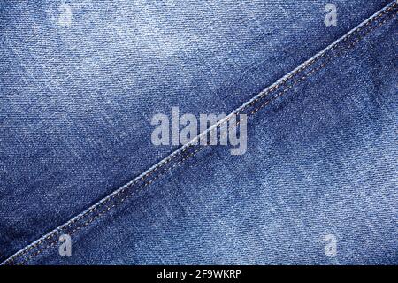 Blue jeans texture, diagonal seam closeup, thread stitch line, jean textile background, blue denim backdrop, faded jeans pattern, shabby indigo jeans Stock Photo