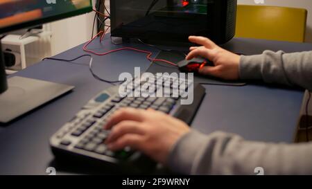 Closeup of player hands using RGB keyboard in gaming home studio. Digital gamer using professional equipment for first shooter video game person competition late at night in living room Stock Photo