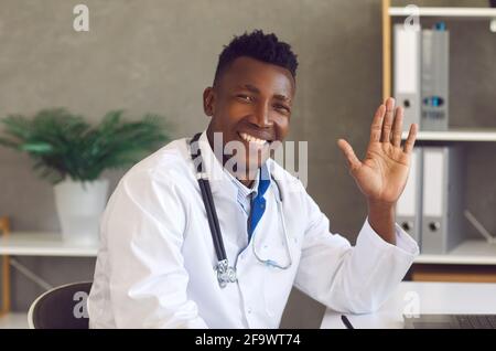Headshot of happy African-American doctor looking at camera, smiling and waving hand Stock Photo
