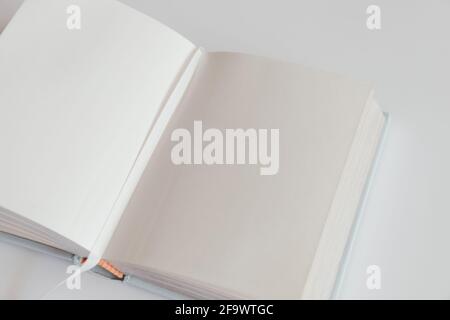 Open blank book on a white background with a bookmark. Notebook inside mockup. Empty open book in square format. Design concept - top view of white no Stock Photo