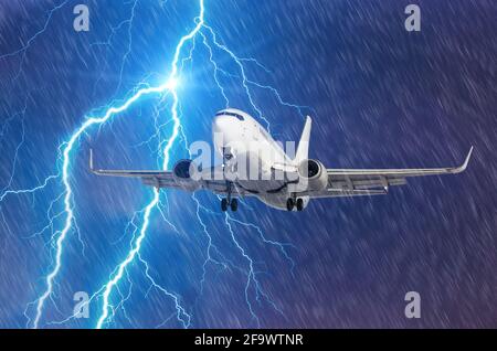 Lightning hits strike during a heavy downpour, behind a flying plane Stock Photo