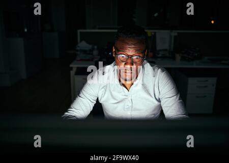 Focused young african businessman working at his office desk late in the night Stock Photo
