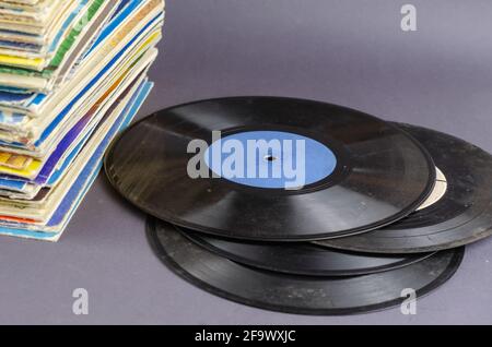 A collection of old comics, magazines, and vinyl records on a gray background. Lots of old shabby prints and music records from the last century. Coll Stock Photo