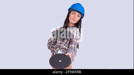 Banner, long format isolated gray background. Serious brunette woman showing Hard woman holding two disks for radial grinder tool. Repair woman, force Stock Photo