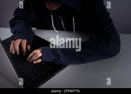 Closeup of a hacker typing and working on his laptop Stock Photo