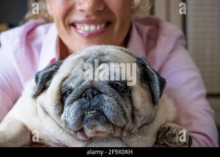 Happy woman hug his dog pug with love and frienship . concept of best friend forever and animal owner enjoying time at home - close up of affection an