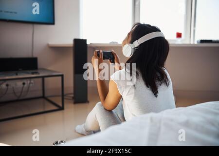 Young woman in headphones playing video game at home Stock Photo