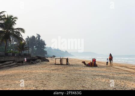 View of Ganapatipule beach with people enjoying camel rides during morning time, Ratnagiri, Maharashtra, India. Stock Photo