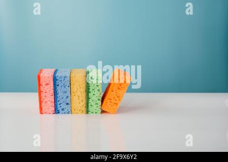 A pile of colorful cleaning sponges on blue background. Cleaning service and spring cleaning concept Stock Photo