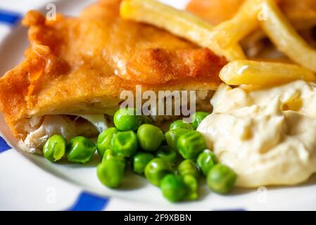 Traditional street food and restaurant meal, breaded fried fish and chips with pea and mayonnaise. Closeup. Stock Photo