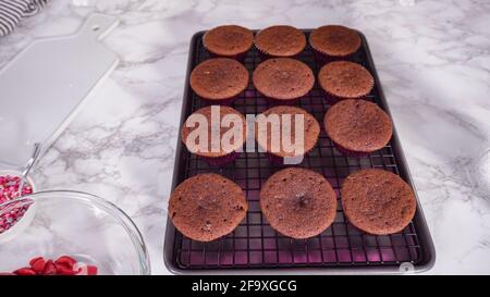 Step by step. Cooling red velvet cupcakes on a kitchen drying rack. Stock Photo