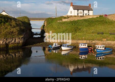 The Cut, an 18th century channel, at Seaton Sluice in Northumberland, England. Fishing boats are moored in the harbour below The Kings Arms pub. Stock Photo