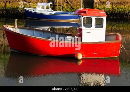 Fishing boats in harbour. The boats have red and blue hulls. Stock Photo