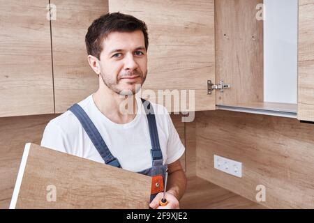 Man assembling kitchen cabinet. Handyman repair kitchen furniture Stock Photo