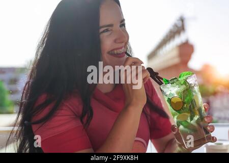 Close-up portrait of smiling teenage girl with braces drinking a mojito cocktail. Stock Photo