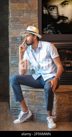 portrait of a young dark skinned man in panama hat, with a cigar, in his thought. Stock Photo