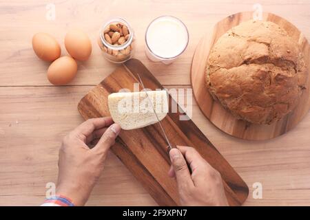 flat composition of of man hand cutting cheese on chopping board  Stock Photo