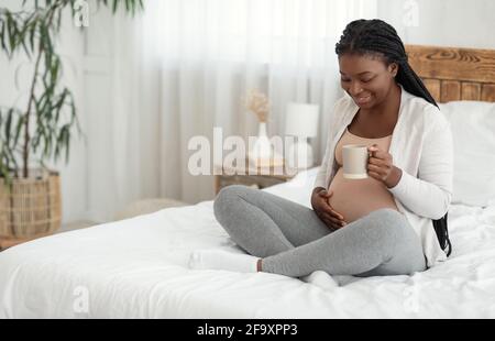 Smiling Black Expectant Mother Relaxing At Home With Cup Of Herbal Tea Stock Photo