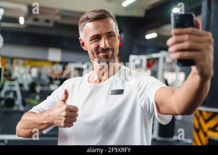 Attractive confident young man taking selfie while standing in the gym Stock Photo
