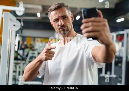 Attractive confident young man taking selfie while standing in the gym Stock Photo