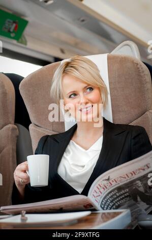 Young woman enjoying a cup of tea on a train in the UK. Stock Photo