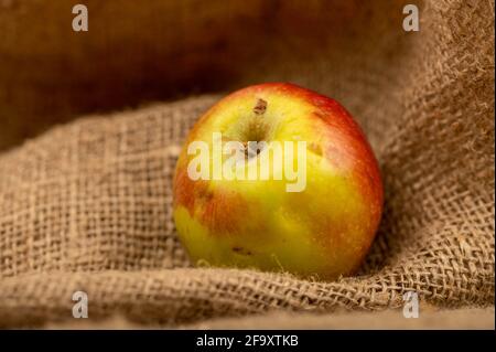 Fresh green apple on a homespun cloth with a rough texture. Close-up selective focus. Stock Photo