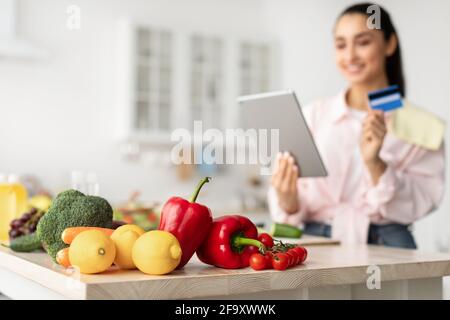 Woman shopping online using tablet and credit card in kitchen Stock Photo
