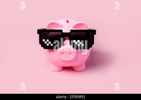 Pink piggy money bank with black sunglasses on a pink background Stock Photo