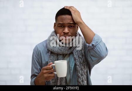 African Man Having Headache And Fever Standing Over White Wall Stock Photo