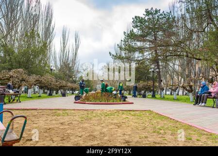 Kerch, Russia - April 2021: Janitors clean the lawns in spring city. Street sweepers with rake, work of housing and communal services, people work, ga Stock Photo